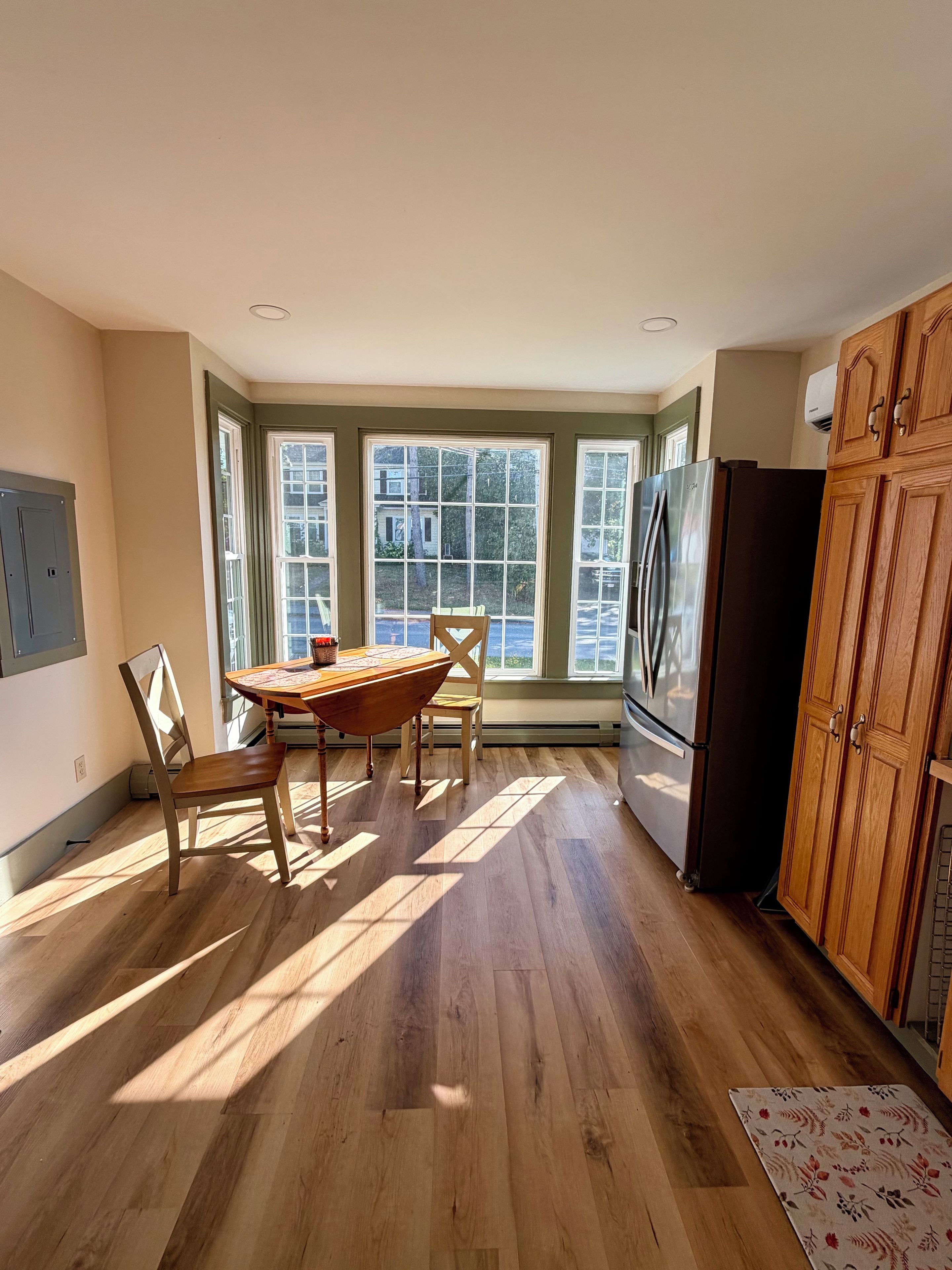A kitchen with a dining table, chairs, a refrigerator, and wooden cabinets.