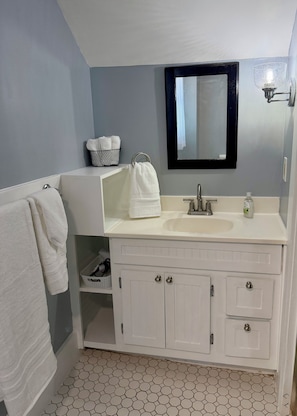 A bathroom with a white vanity, a mirror, and a hexagonal tile floor.
