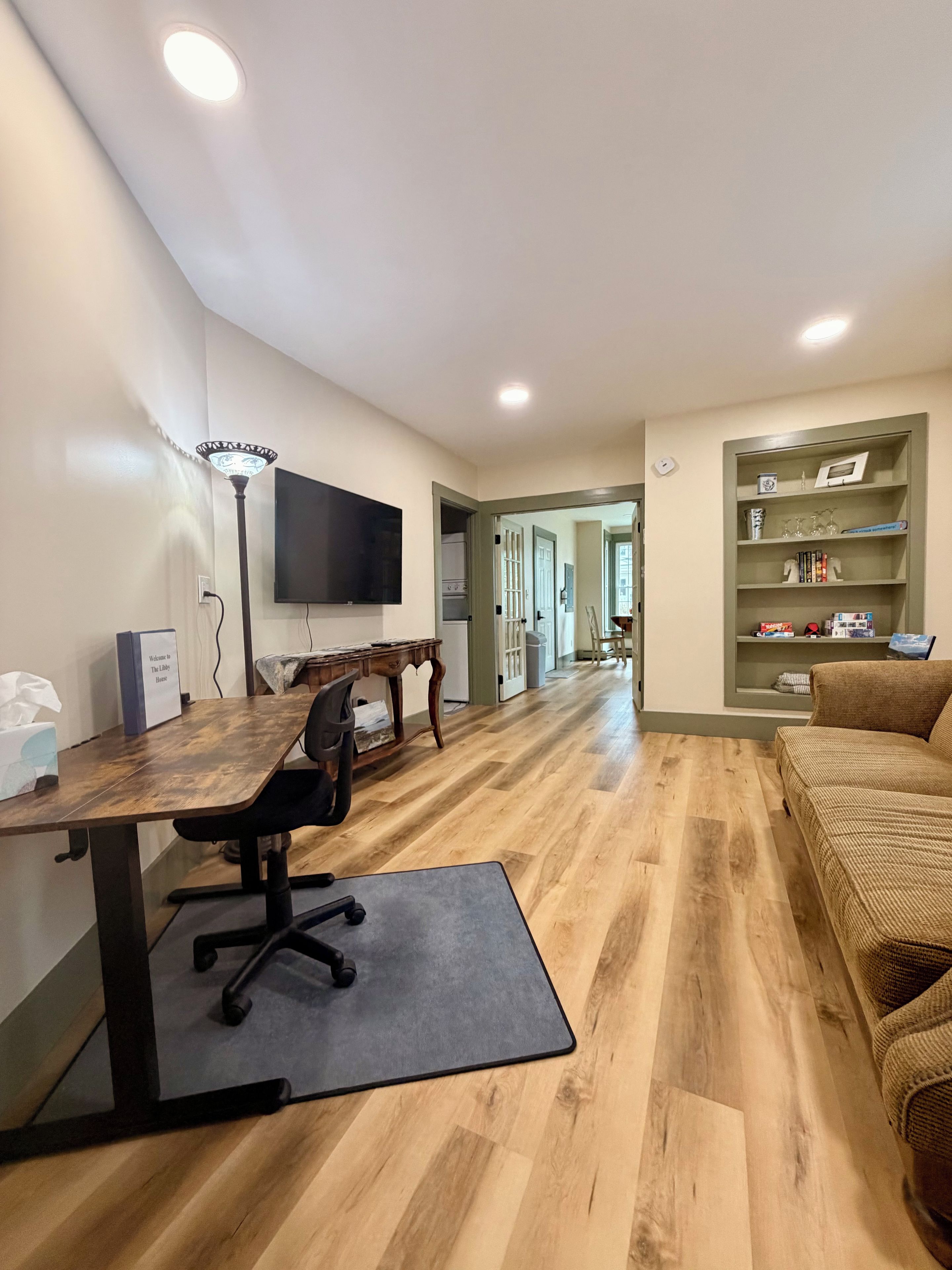 Una sala de estar moderna con piso de madera, un sofá, una mesa de centro y un televisor montado en la pared.