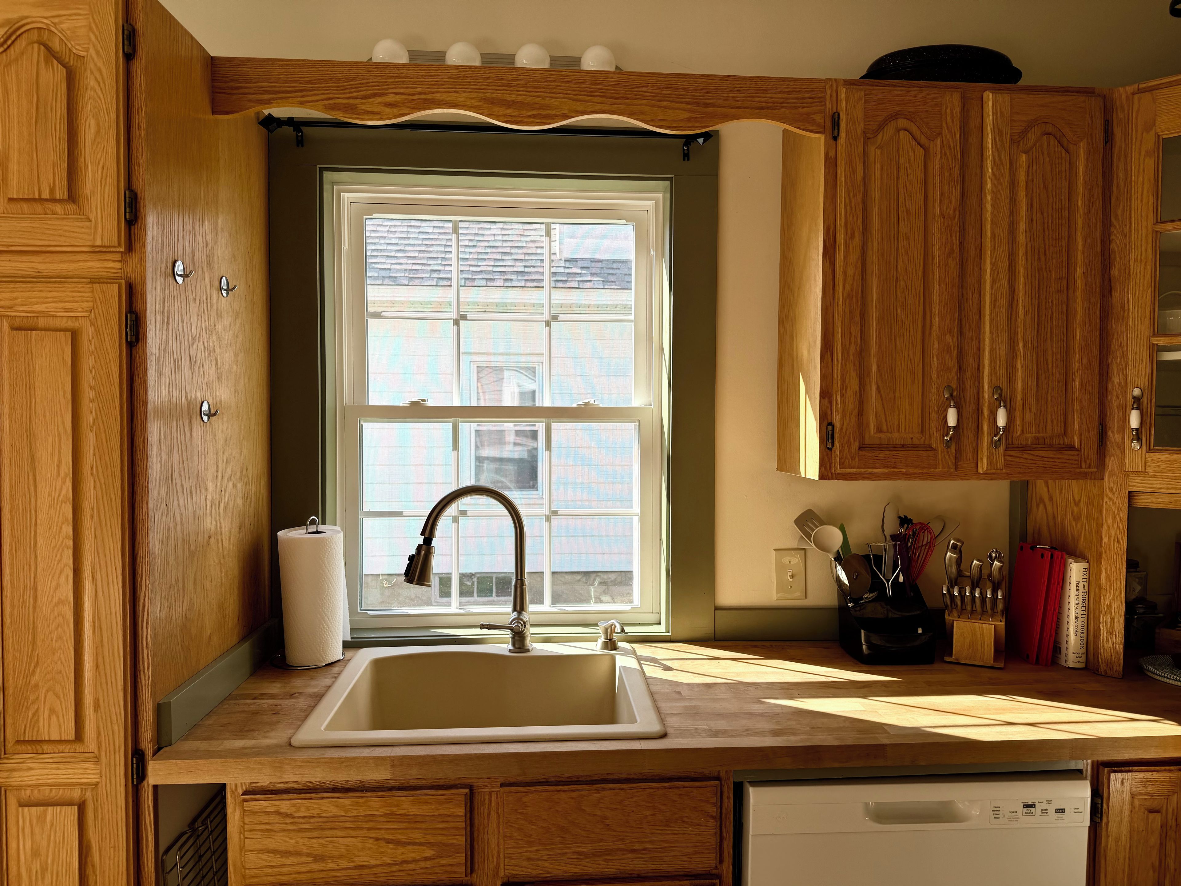 A kitchen with wooden cabinets, a stainless steel sink, and a window above the sink.