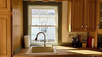 A kitchen with wooden cabinets, a stainless steel sink, and a window above the sink.
