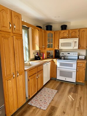 A kitchen with wooden cabinets, a microwave, an oven, and a dishwasher.