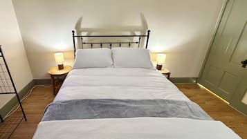 A single bed with a metal frame, two bedside tables with lamps, and a door to the right.