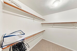 Een kast met houten planken en een kledingroede met kleren.