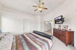 A bedroom with a bed, a dresser, a television, and a ceiling fan. - The Buckskin Getaway- Private Pool & Putting Green (Peoria)