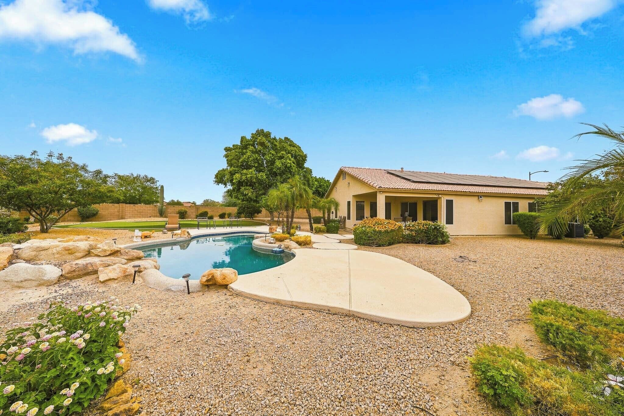 A residential property with a swimming pool, a house, and a well-maintained garden.