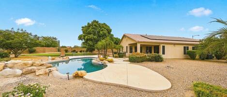 A residential property with a swimming pool, a house, and a well-maintained garden.