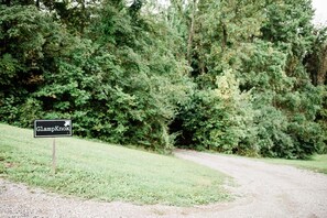 A sign with the text 'GlampKnox' pointing to a gravel path leading through a wooded area.