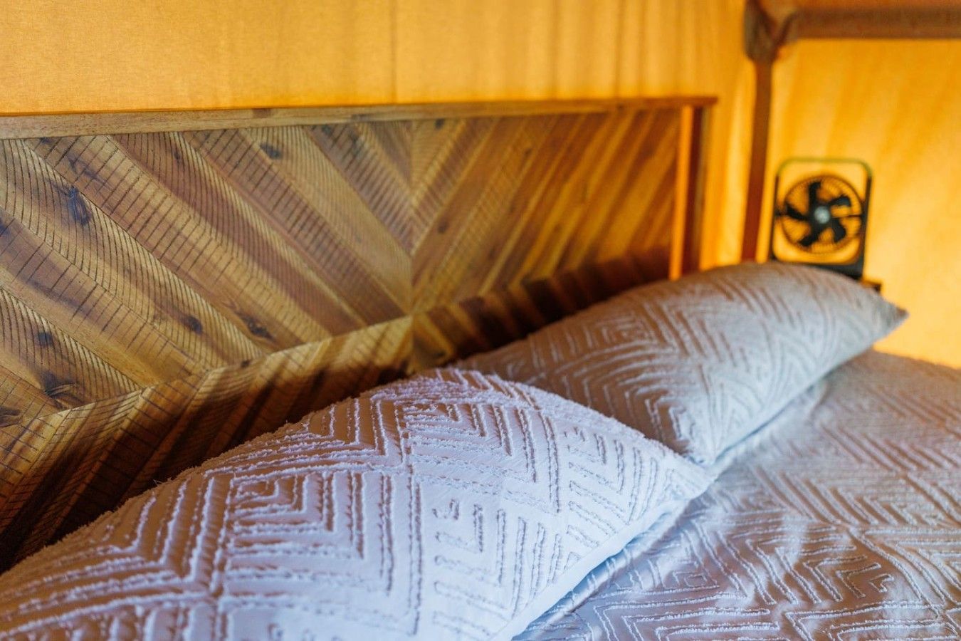Un letto con biancheria a motivi decorativi e una testiera in legno.