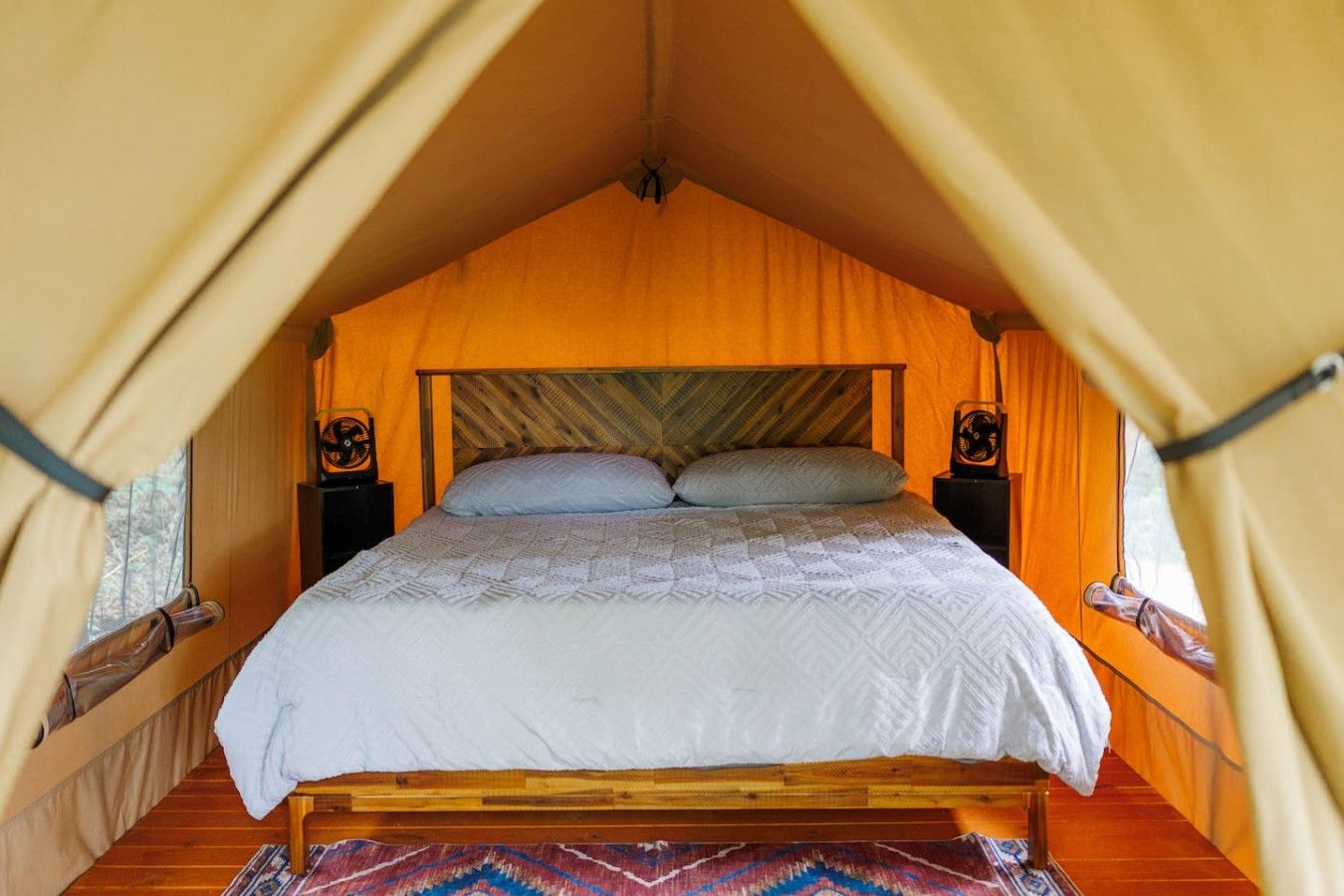 Una tenda con un letto, due comodini e un tappeto decorato.
