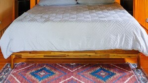 Tenda com uma cama, duas mesas de cabeceira e um tapete estampado.