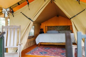 Una tenda amb un llit, una cadira i un estot.