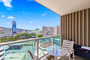 A balcony with a glass railing, a table, and a sofa. - 11F-Upscale King Suite-Corner Unit-Ala Moana Hotel (Honolulu)