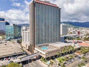 A high-rise hotel with a pool, surrounded by other buildings and a mountainous backdrop. - 11F-Upscale King Suite-Corner Unit-Ala Moana Hotel (Honolulu)
