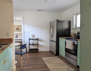A compact kitchen with a refrigerator, oven, and a small dining area.