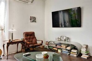 A living room with a leather armchair, a glass coffee table, a bookshelf, and a large abstract painting on the wall. - Artist's Townhouse in Capitol Hill w/ AC + Rooftop (Seattle)