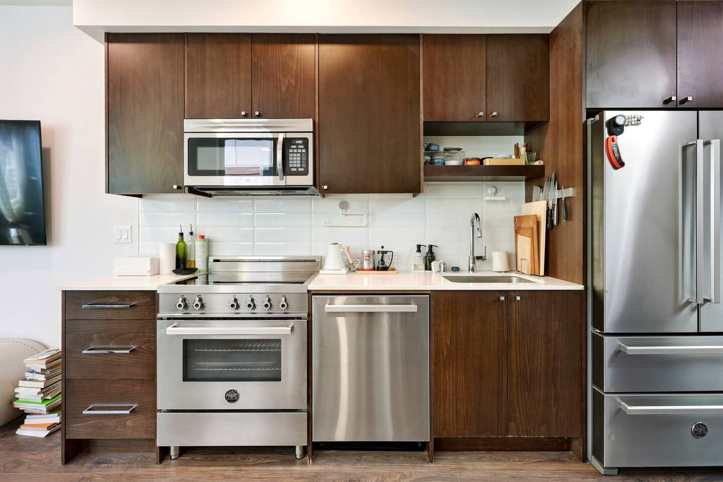 Una cocina moderna con electrodomésticos de acero inoxidable, armarios de madera y un salpicadero de azulejos blancos.