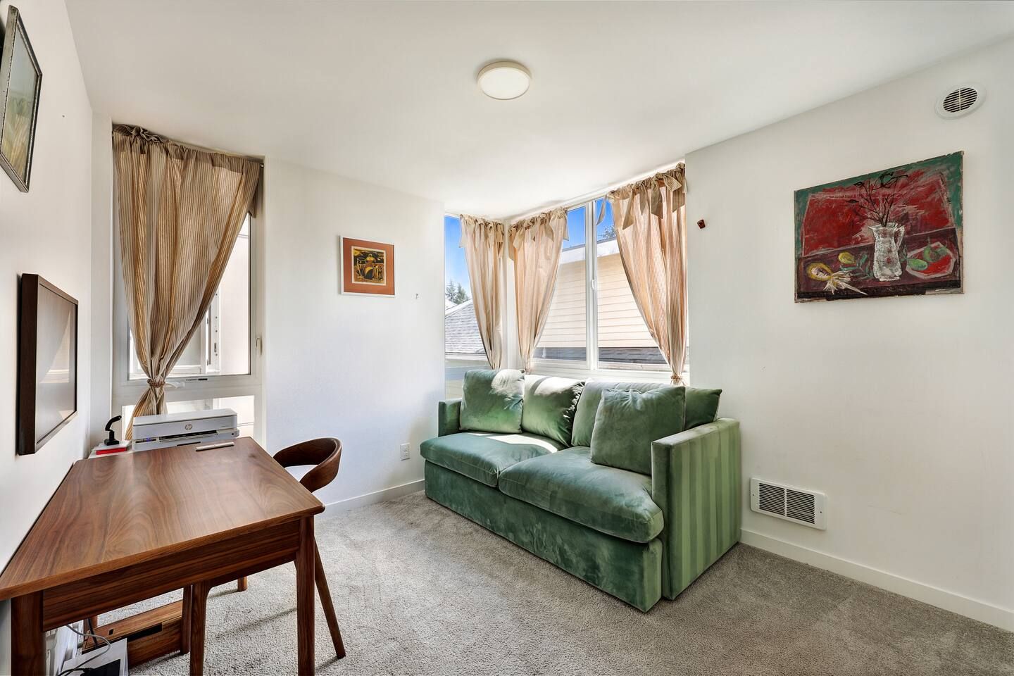 Ein Zimmer mit einem grünen Sofa, einem Holztisch und einem Fenster mit Vorhängen.