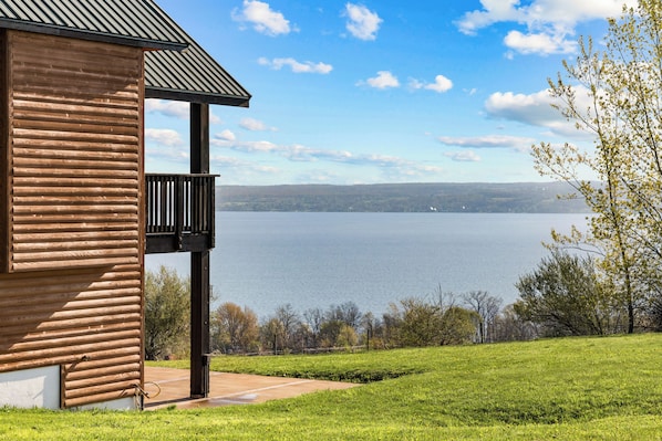 A wooden cabin with a balcony overlooking a lake.