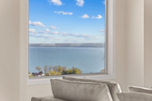 A room with a large window overlooking a body of water and a distant landscape.