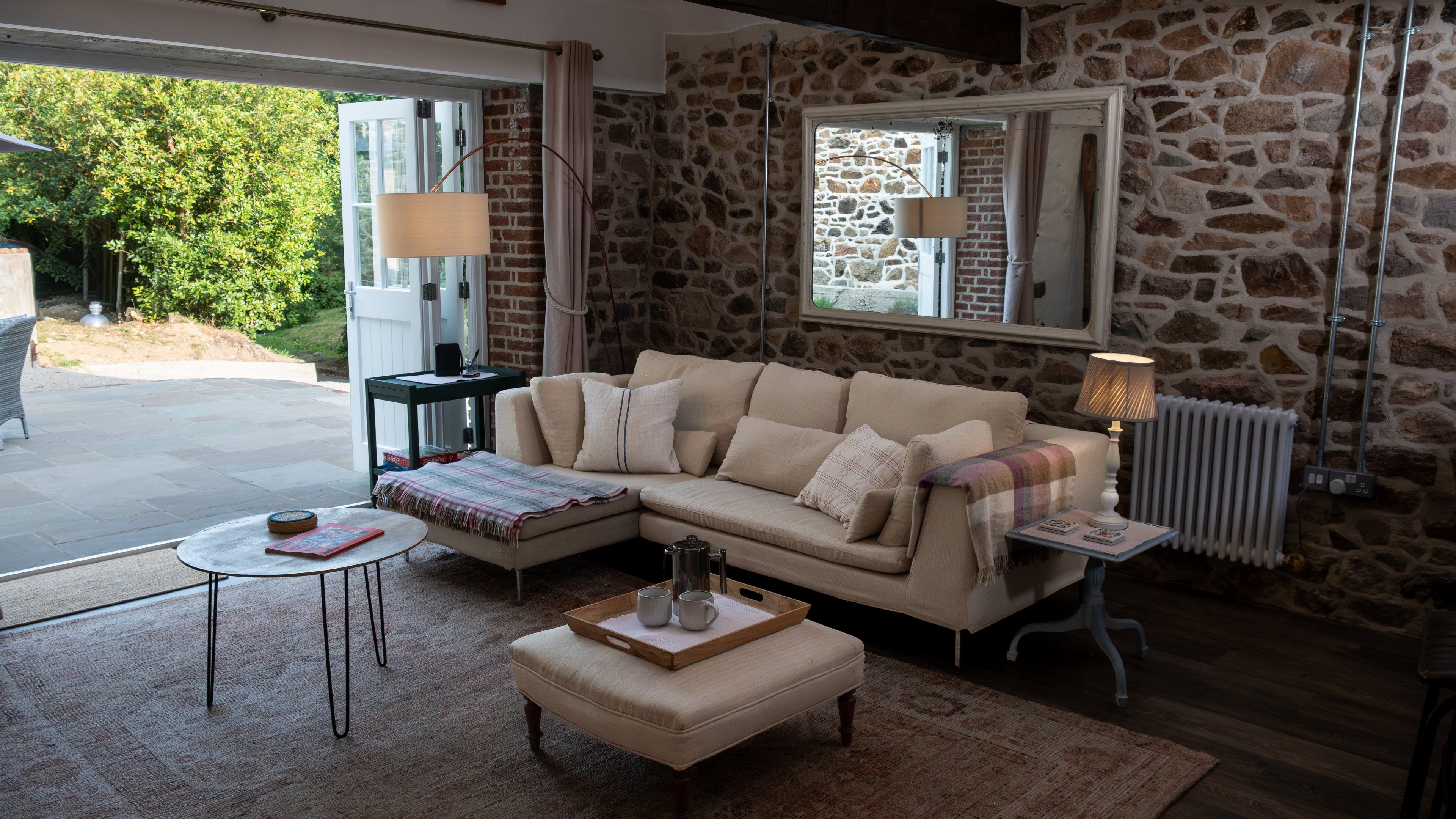 Un salon chaleureux avec un mur en pierre, un canapé, une table basse et un radiateur.