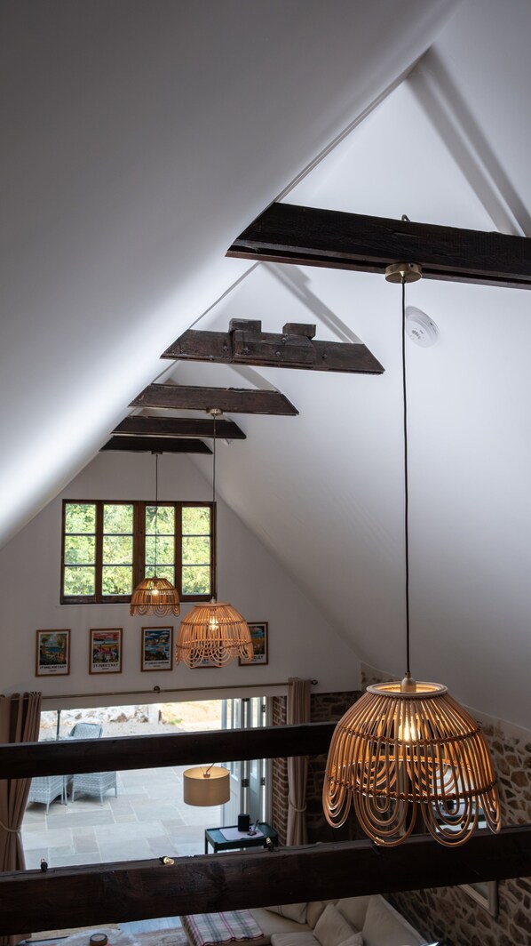 A room with a sloped ceiling, wooden beams, and a view through a window.