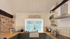 A kitchen with a stone wall, a window, and a wooden countertop.
