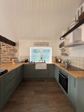 A kitchen with a stone wall, a window, and a wooden countertop.