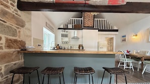 A bar area with stools, a counter, and a brick wall. - Peaceful Granite Cottage: Walk to St Brelade's Bay Beach and St Aubin Harbour (St Brelade)