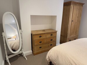 Quarto com cama, cómoda de madeira e espelho.