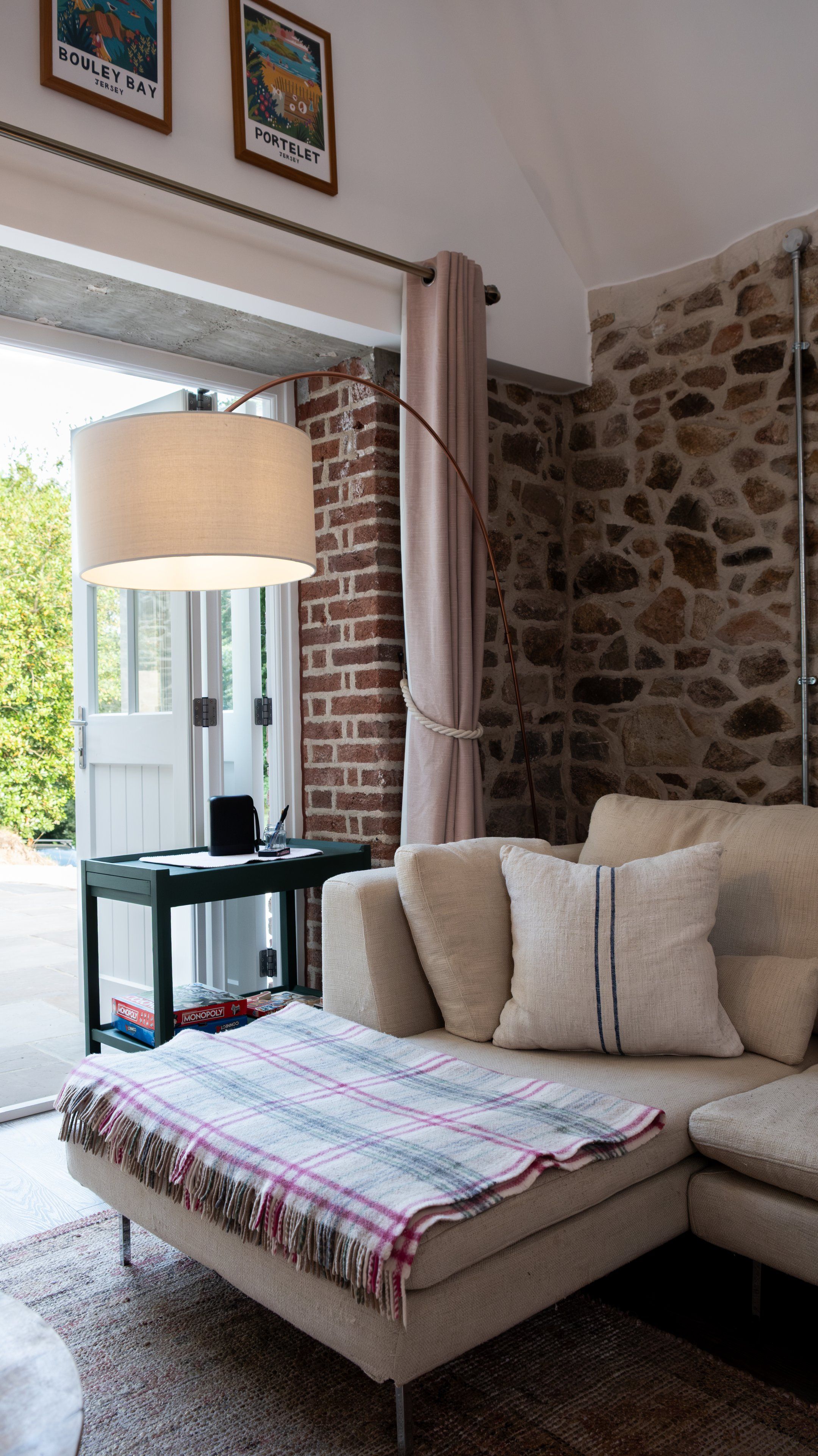 Una habitación con sofá, lámpara, pared de ladrillo y ventana.