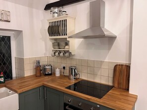 A kitchen with a wooden countertop, a stainless steel range hood, and a built-in oven.