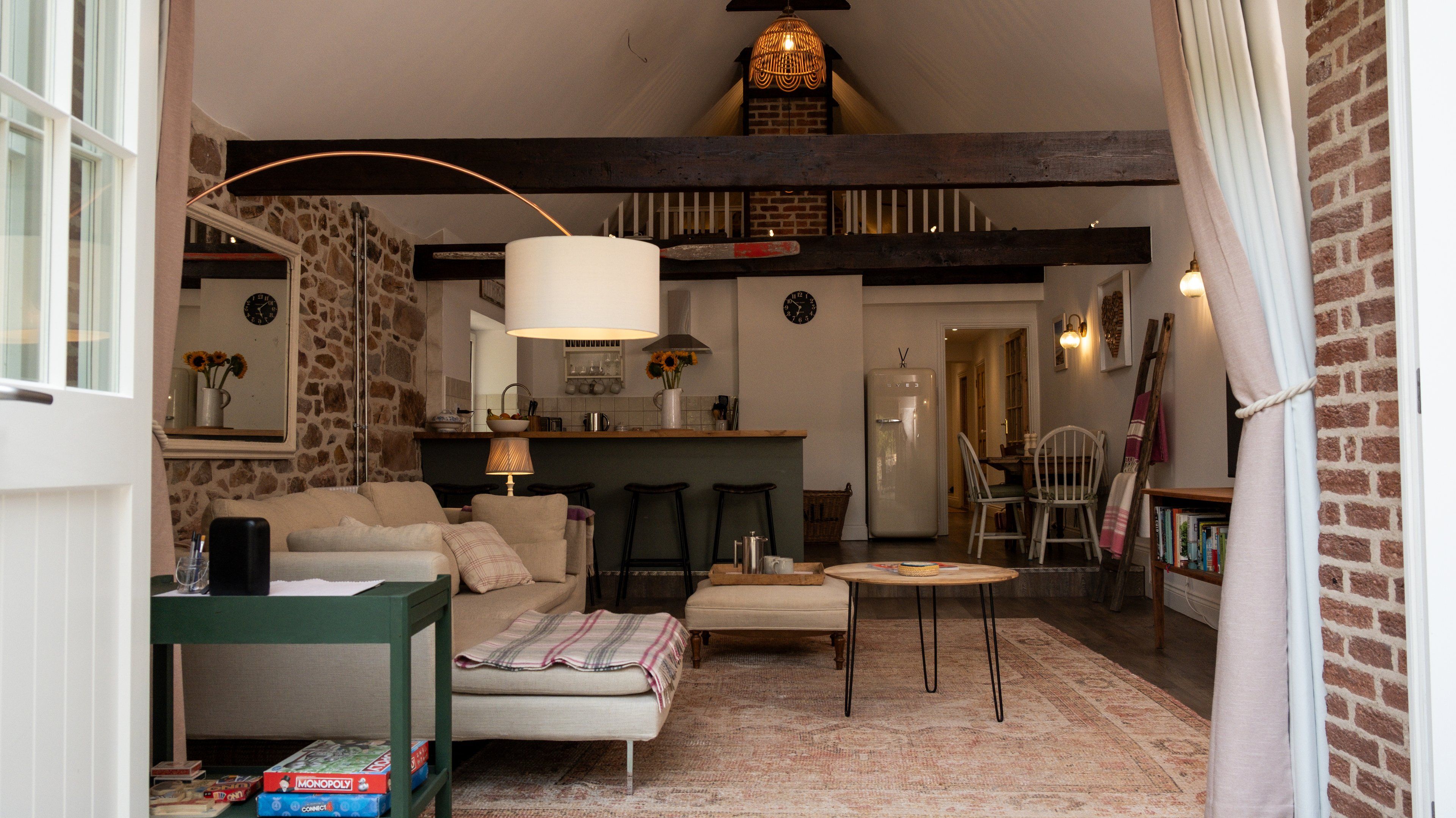Un salon confortable avec un canapé, une petite table, une lampe et un coin cuisine équipé d’un réfrigérateur et d’un évier.
