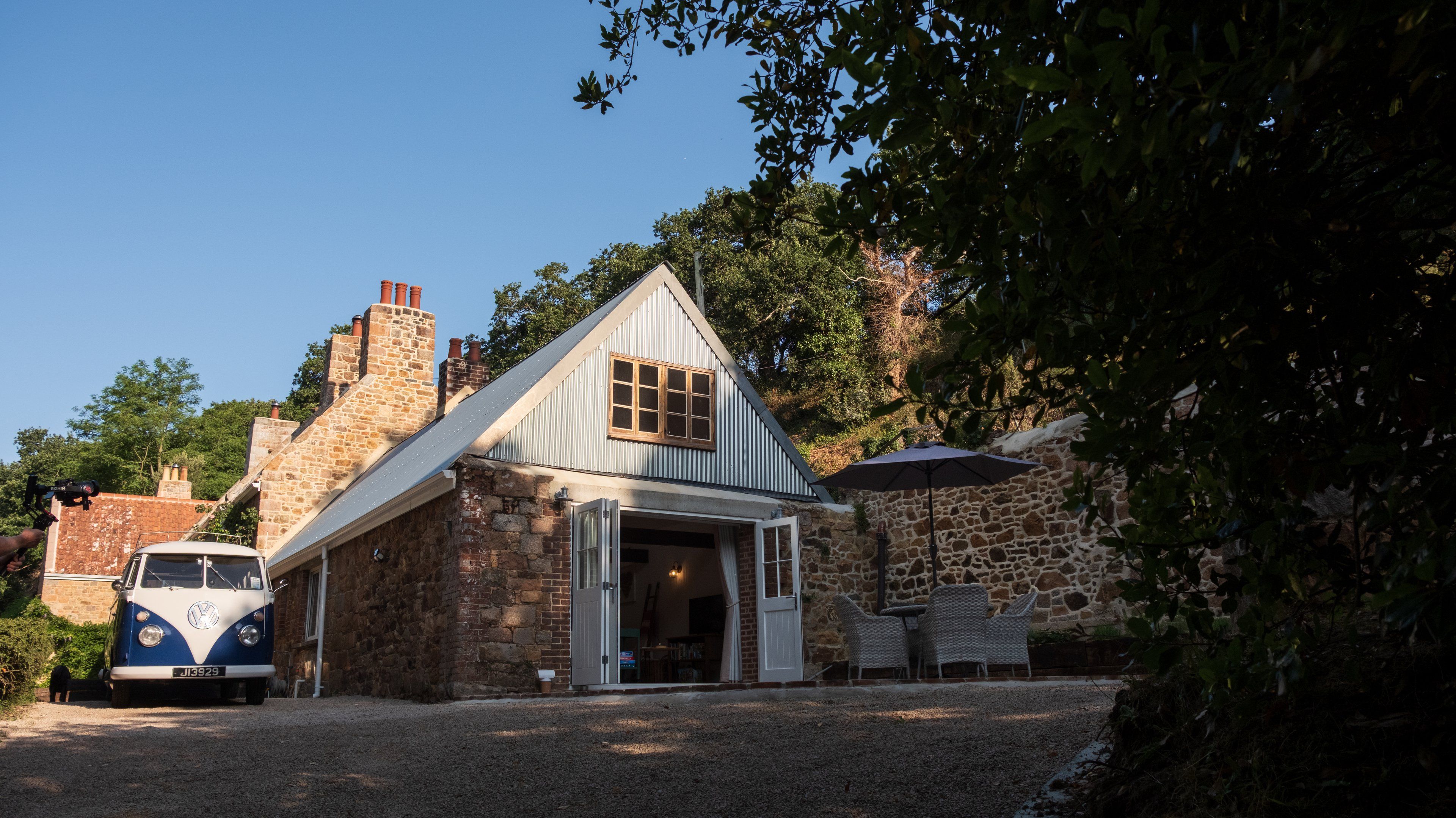 Una casa de piedra con techo inclinado, un garaje y un camino de entrada de grava.