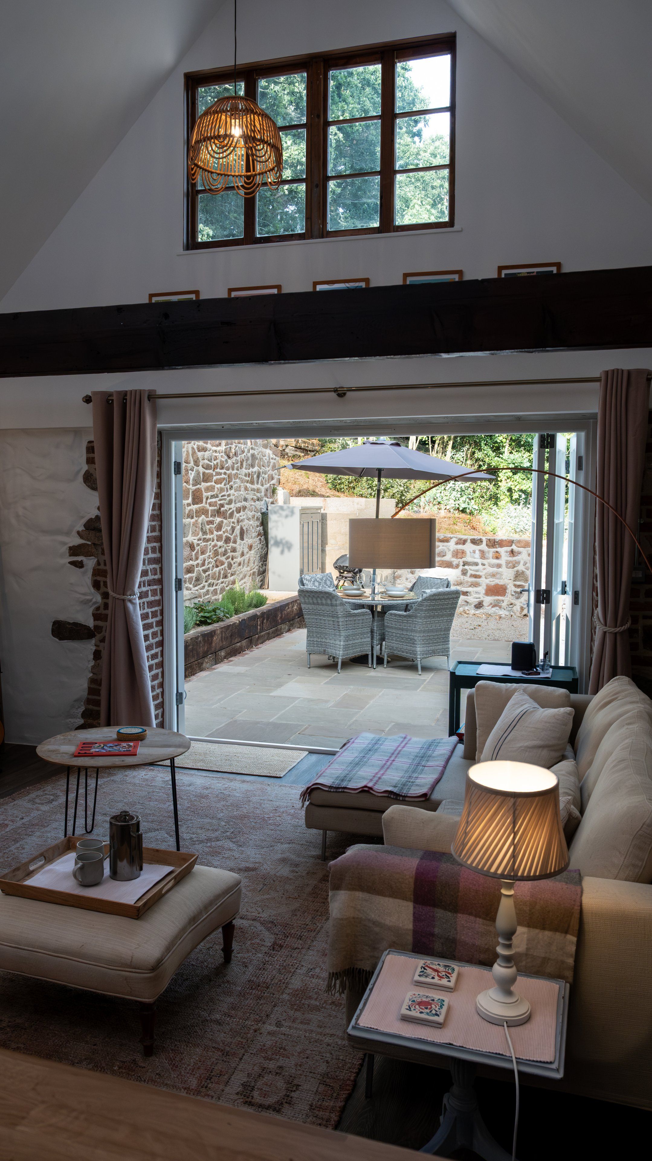 Una sala de estar acogedora con una pared de piedra, un comedor con mesa y sillas, y un ventanal con vistas al exterior.