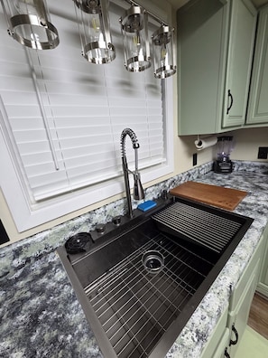 A kitchen with a black sink, a faucet, and a built-in grill.