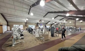 Une salle de sport intérieure équipée de divers appareils d’exercice, dotée d’un grand espace ouvert et d’un plafond haut.