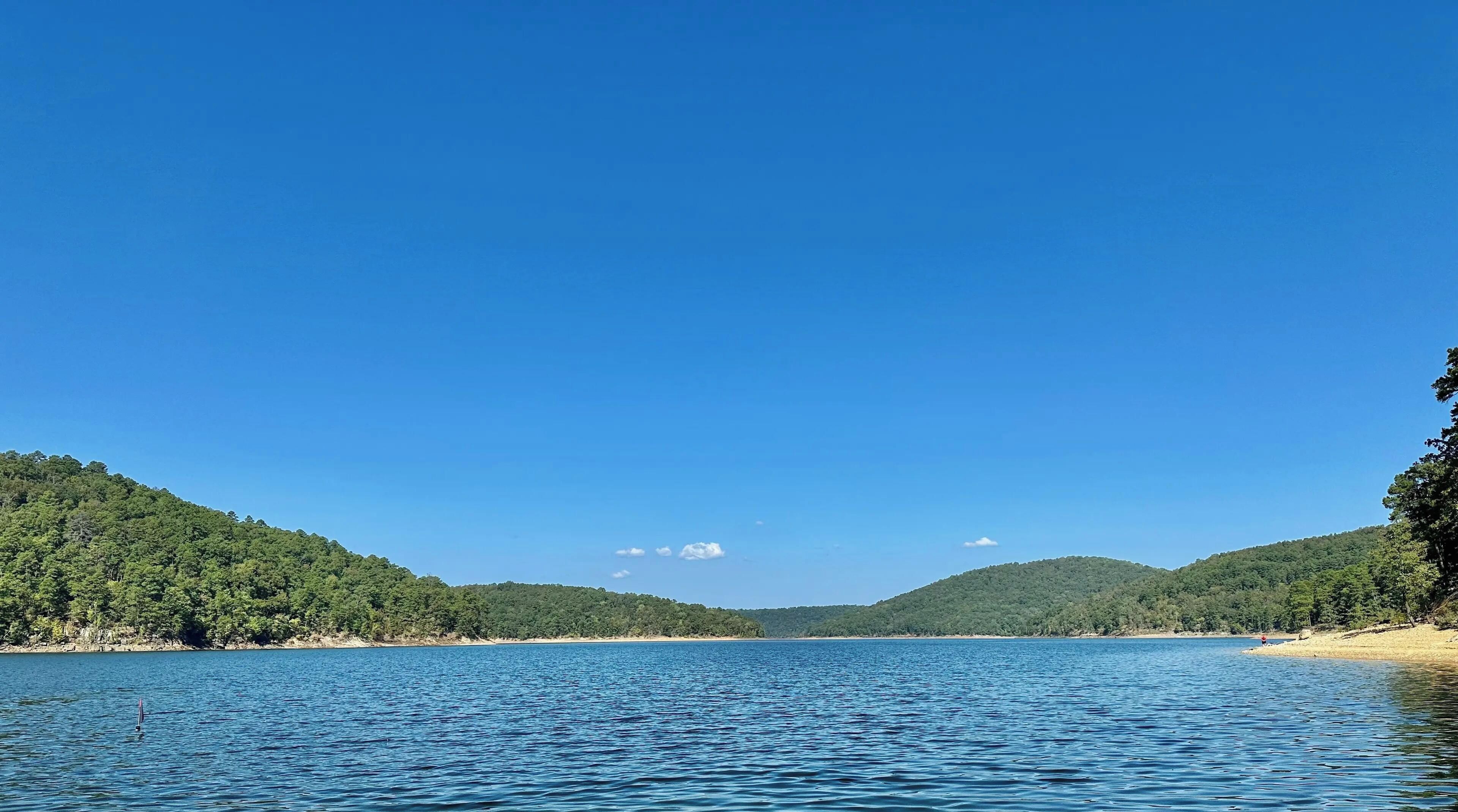 A calm lake with forested hills in the background.