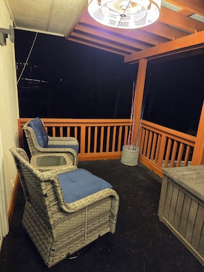 A balcony with wicker furniture, a metal trash can, and a ceiling light fixture.