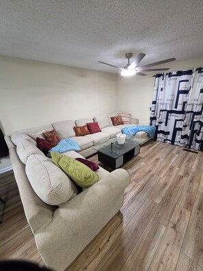 A living room with a sofa, a coffee table, and a ceiling fan.