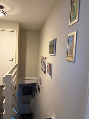 A hallway with a white railing, a door, and several framed pictures on the wall. - Cosy and bright spacious 3 bedroom house in a quiet cul de sac area in Culloden (Culloden)