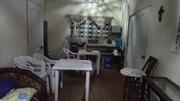 A compact living space with a dining area, a small kitchen, and a seating area with a sofa and chairs.