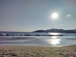 A beach with waves, a boat, and a distant mountain. - BLUE SEA HOUSE (Playa Blanca)