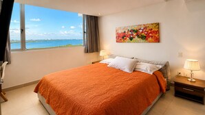 Ein Schlafzimmer mit einem großen Bett, Blick auf das Wasser und einem Gemälde an der Wand.
