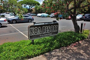Schild für KOA RESORT, mit freier Sicht auf den Parkplatz und die umliegende Bepflanzung.