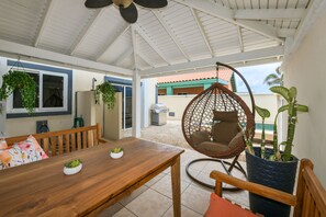 Eine Terrasse im Freien mit einem Holztisch, Stühlen, einem Hängestuhl und Topfpflanzen.