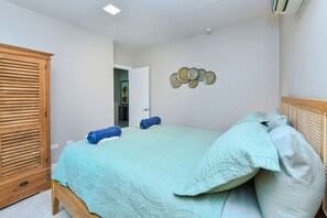 Ein Schlafzimmer mit einem Bett, einem Kleiderschrank und einer Tür zu einem weiteren Raum.