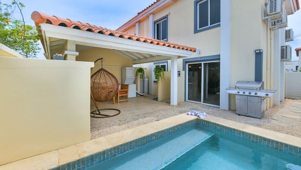 Una proprietà residenziale con piscina, patio coperto e area barbecue.