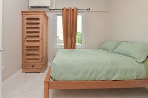 Un dormitorio con una cama, un armario de madera y un equipo de aire acondicionado.