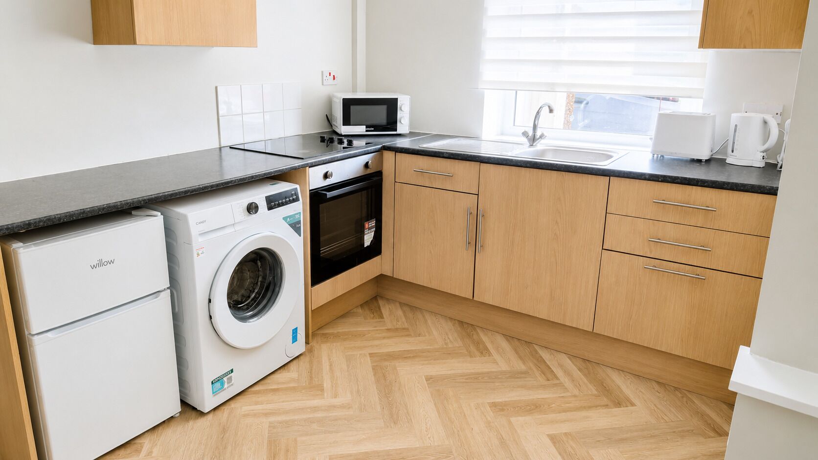 A compact kitchen with a washing machine, a microwave, and a toaster.